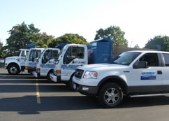 Fleet of AM Shield waterproofing service vehicles parked, showcasing company branding and readiness for drainage and waterproofing solutions.