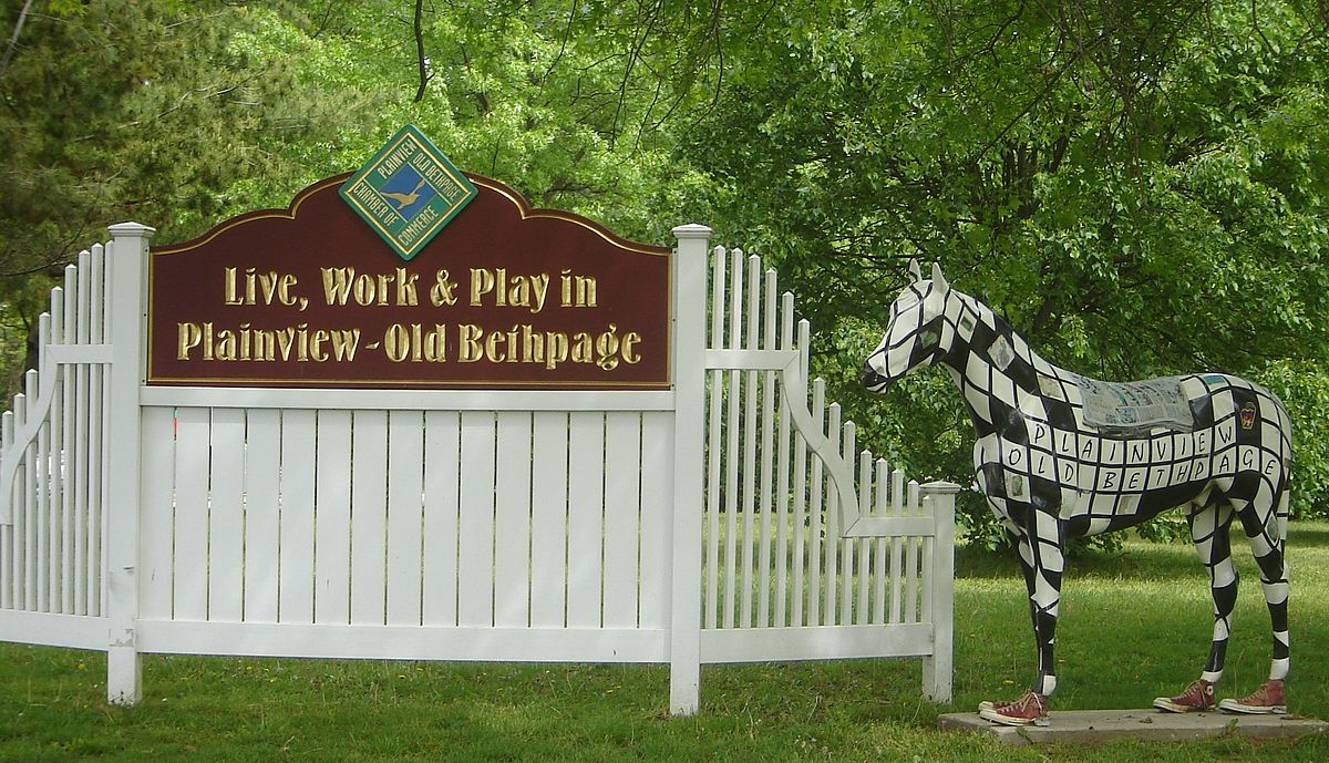 Sign welcoming visitors to Plainview-Old Bethpage, featuring a decorative horse statue and greenery, emphasizing community engagement and local charm.