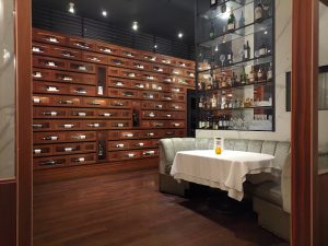 Elegant restaurant interior featuring a cozy booth with a white tablecloth, wooden shelves displaying liquor bottles, and a warm ambiance, reflecting the upscale dining experience at PRIME 1024 Restaurant in North Hills, NY.