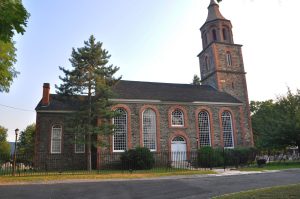 St. Paul's Church National Historic Site in Mount Vernon, NY, featuring a stone facade, tall bell tower, and surrounding greenery.