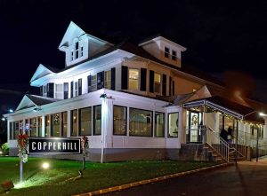 Copperhill Restaurant exterior at night, featuring a well-lit building with a sign, surrounded by manicured lawn, highlighting its location as a dining option in North Hills, NY.