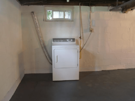 Washer and dryer in a clean, dry basement with window and ventilation, emphasizing mold-resistant environment for effective mold remediation solutions.