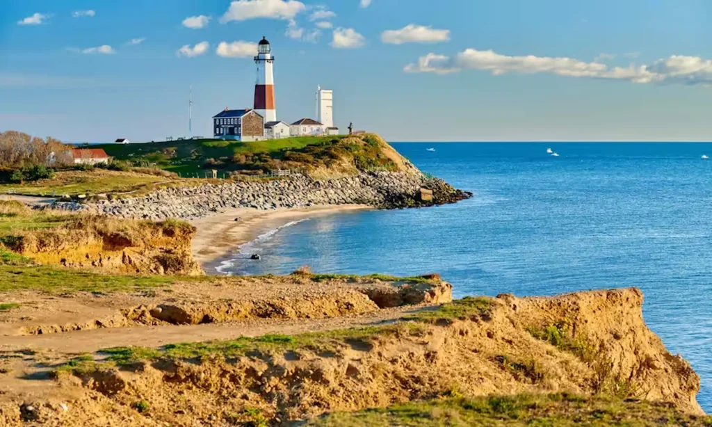 Lighthouse on a coastal cliff overlooking the ocean, surrounded by rocky shoreline and grassy landscape, representing coastal protection and environmental resilience.